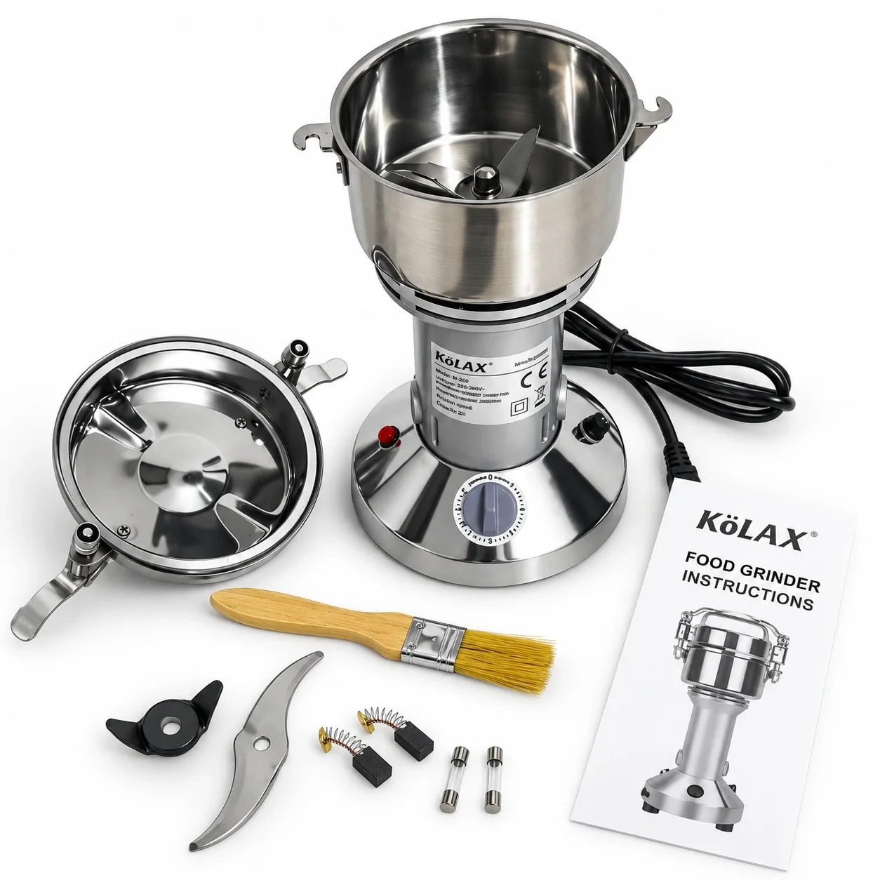 Open KöLAX powder grinder with its lid, cleaning brush, spare blades, carbon brushes, fuses and instruction manual displayed alongside.